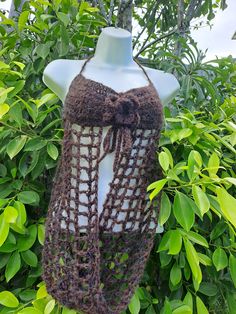 a crocheted brown shawl hanging from a tree