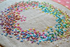 a close up of a cross stitch pattern on a piece of cloth with colored sprinkles