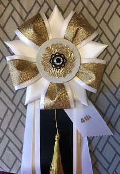 a white and gold ribbon with a tassel on it's end is attached to a black box