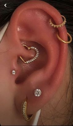 an ear with three different types of piercings on top of the ear and one is gold