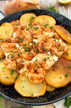 a pan filled with shrimp and potatoes on top of a table