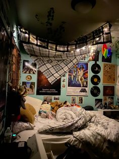 an unmade bed in a room with posters on the wall and lights hanging from the ceiling