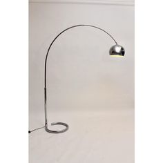 a chrome plated floor lamp with a curved arm and an adjustable bulb, on a white background