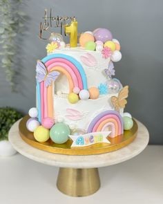 a birthday cake decorated with rainbows and balloons