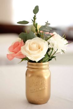 a gold mason jar filled with white and pink flowers