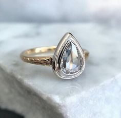 a close up of a ring on a white marble surface with a diamond in the center