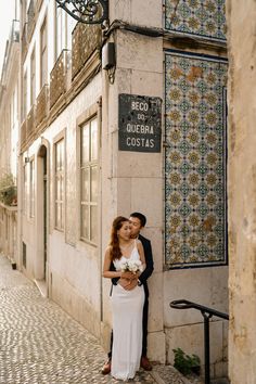 a couple standing next to each other in front of a building