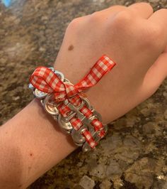 a person's hand wearing a red and white checkered ribbon on their wrist