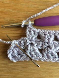 the crochet pattern is being worked on with two knitting needles