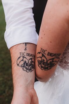 two people holding hands with tattoos on their arms