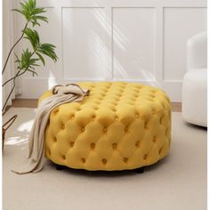 a yellow foot stool sitting on top of a white floor next to a potted plant