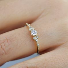 a woman's hand with a diamond ring on top of her finger and the bottom half of her wedding band