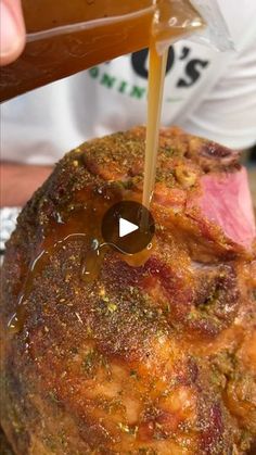 a person pouring sauce on top of a roast beef