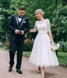 a man in a tuxedo and a woman in a wedding dress walking down a path