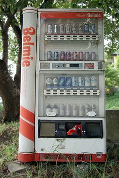 an old vending machine sitting in the grass