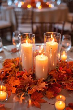 candles are lit on a table with autumn leaves