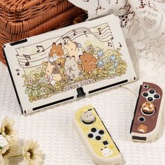 two video game controllers sitting on top of a table next to a box with cartoon characters