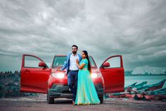 a man and woman standing next to a red car