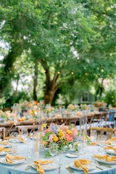 an outdoor table set up with yellow and blue plates, napkins and place settings