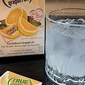 a glass filled with water next to a carton of grapefruit and a box of lemonade