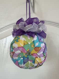 a decorative ornament hanging from a hook on a door handle, decorated with colorful flowers