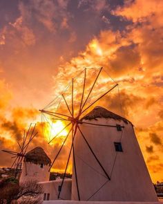 two windmills with the sun setting behind them