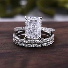 an engagement ring and wedding band set with a princess cut diamond in the center on a wooden surface