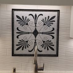 a kitchen sink with a mosaic tile design on the wall above it and a faucet