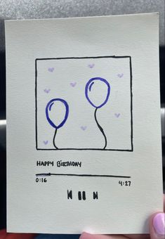 someone is holding up a birthday card with two balloons on it and the words happy birthday written in blue ink