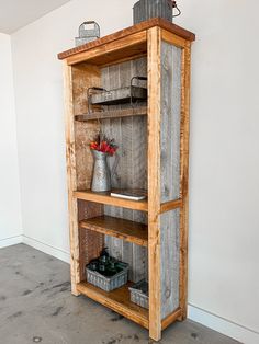 an old wooden shelf with some flowers on top and other items in the bottom section