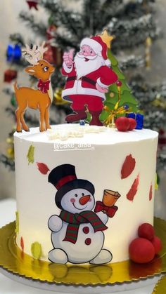 a christmas cake decorated with santa claus and snowman on top, surrounded by holiday decorations