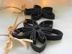 three black bracelets tied with twine on a white surface next to string lights