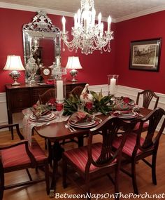 a dining room table set with red chairs and place settings for dinner party or special occasion