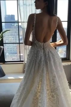 the back of a woman's wedding dress in front of a window with cityscape