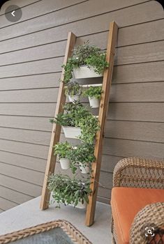 a wooden ladder is holding plants on the side of a house with potted plants