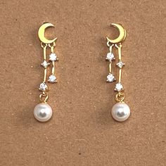 Dainty and lightweight earrings featuring a crescent moon with dangling stars and pearls. Delivered in a box ready for gifting or keeping. Metal: 18kt Gold plated over sterling silver Size: Length is 1 inch Celestial Woman, Woman Earrings, Stars Gold, Earrings Moon, Celestial Earrings, Moon And Star, Lightweight Earrings, Moon And Stars, Moon Stars