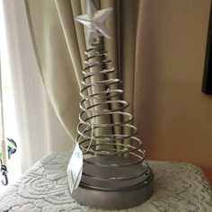 a small metal christmas tree on top of a table next to a window with curtains