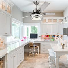 a kitchen with lots of white cabinets and counter top space in front of a window