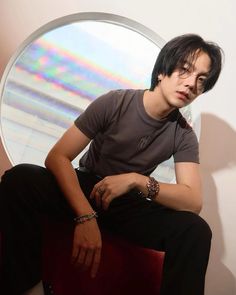 a man sitting on top of a red chair next to a round window