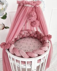 a baby crib with pink bedding and flowers