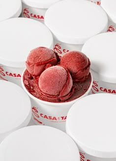 there are many white containers with red desserts in them