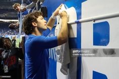 a young man is hanging his jersey on the sidelines at a football game stock photo