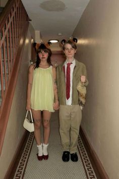 two people dressed up in costumes walking down a hall way with their hands on each other's hips