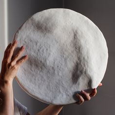 a woman is holding up a large round object