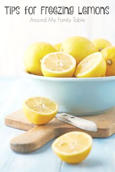 a blue bowl filled with lemons on top of a wooden cutting board next to sliced lemons