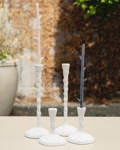 three white vases sitting on top of a table next to each other with trees in them