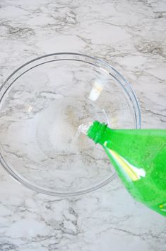 a green toothbrush in a clear bowl on a marble counter