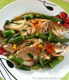 a white plate topped with fish and veggies on top of a green table cloth