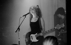 a woman standing in front of a microphone while holding a guitar