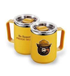 two yellow coffee mugs with bears on the front and one has a brown lid